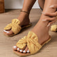Women's Zephyra crushed satin bow slide sandals in champagne gold, featuring a square toe and elegant knotted bow detail, shown on a model's feet with white toenails.