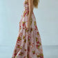 Side view of a bohemian floral gingham maxi dress with a smocked bodice and tiered skirt, worn by a model with blonde hair against a light grey studio background.
