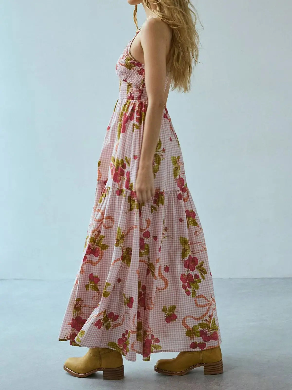 Side view of a bohemian floral gingham maxi dress with a smocked bodice and tiered skirt, worn by a model with blonde hair against a light grey studio background.