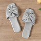Pair of Zephyra Sterling Silver crushed satin bow square-toe flat slide sandals, viewed from top-down on a wooden surface.