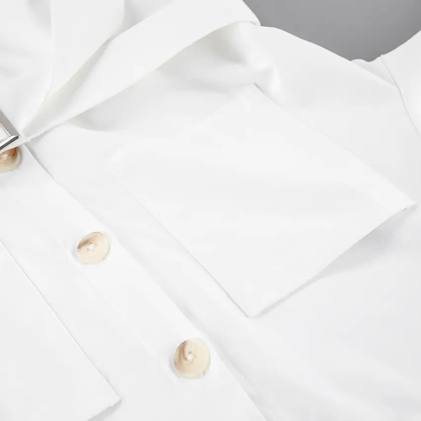 Close-up of an optic white Zephyra playsuit showing pearlescent buttons, chest flap pocket, and matte fabric texture.