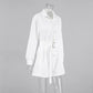 Zephyra elegant white playsuit with shirt collar, long cuffed sleeves, button-down front, chest pockets, and a gold-buckled belt cinching the waist. Tailored shorts shown on a mannequin from a three-quarter angle.
