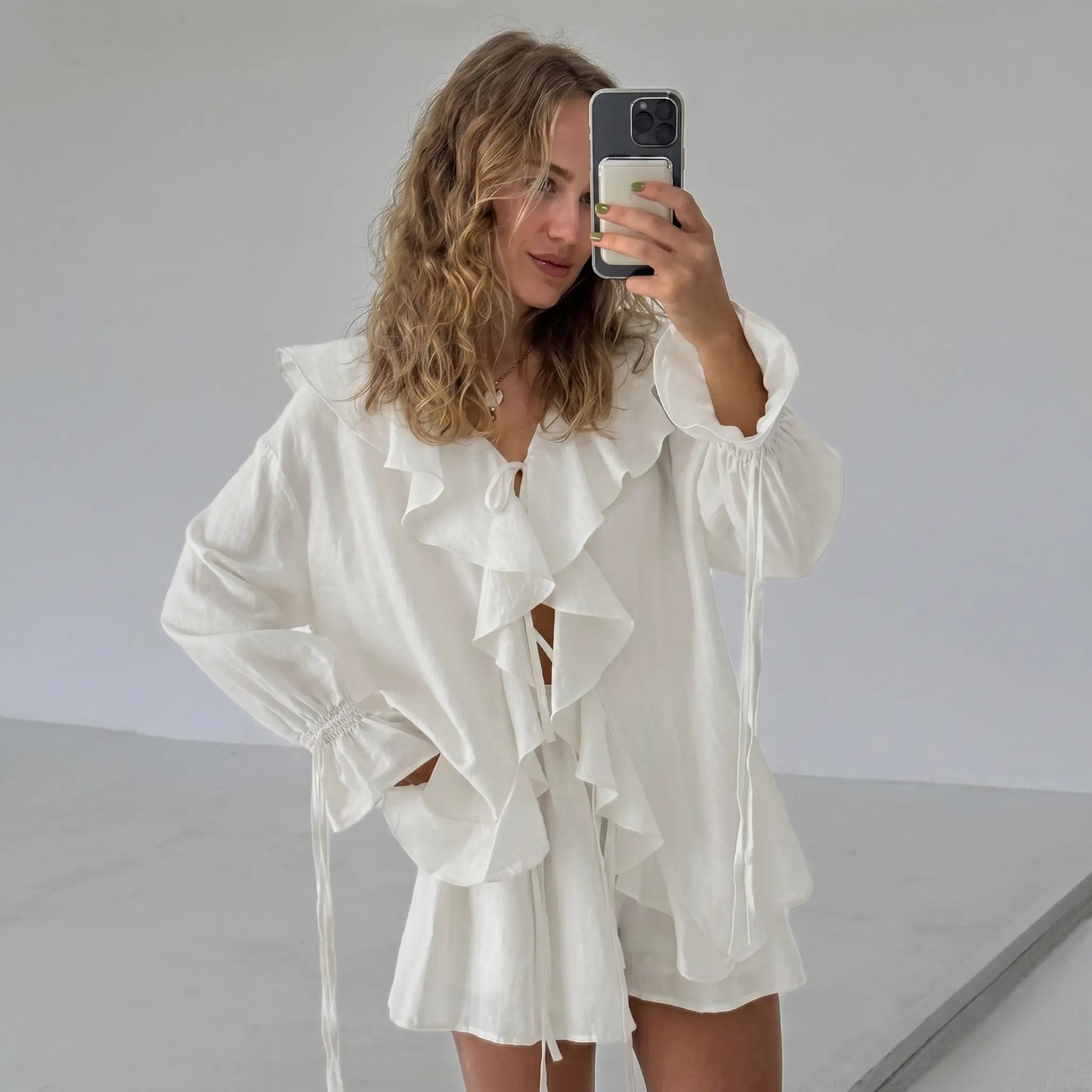Woman wearing an ivory cream bohemian ruffle set with a V-neck tie blouse and relaxed-fit shorts, captured in a natural selfie style.