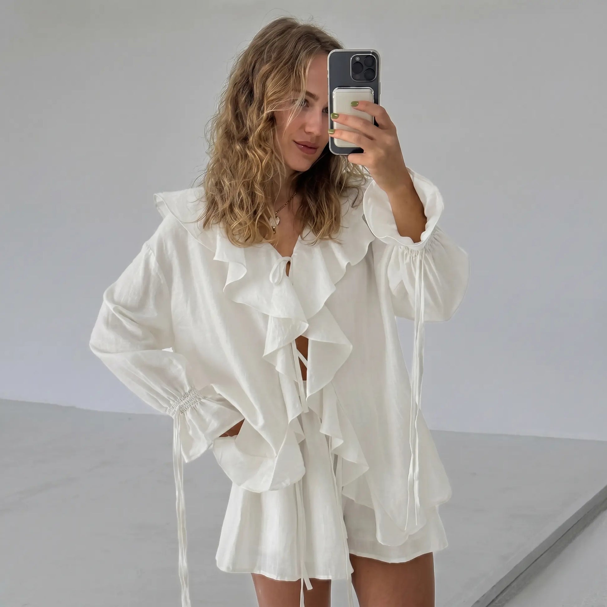 Woman wearing an ivory cream bohemian ruffle set with a V-neck tie blouse and relaxed-fit shorts, captured in a natural selfie style.