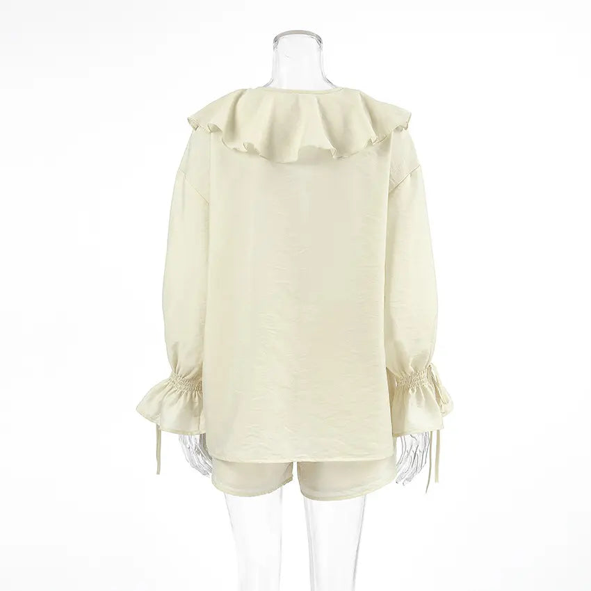 Back view of the Zephyrine ivory cream boho ruffle two-piece set, featuring a loose-fitting blouse with long balloon sleeves and elasticated tie cuffs, paired with high-waisted drawstring shorts.