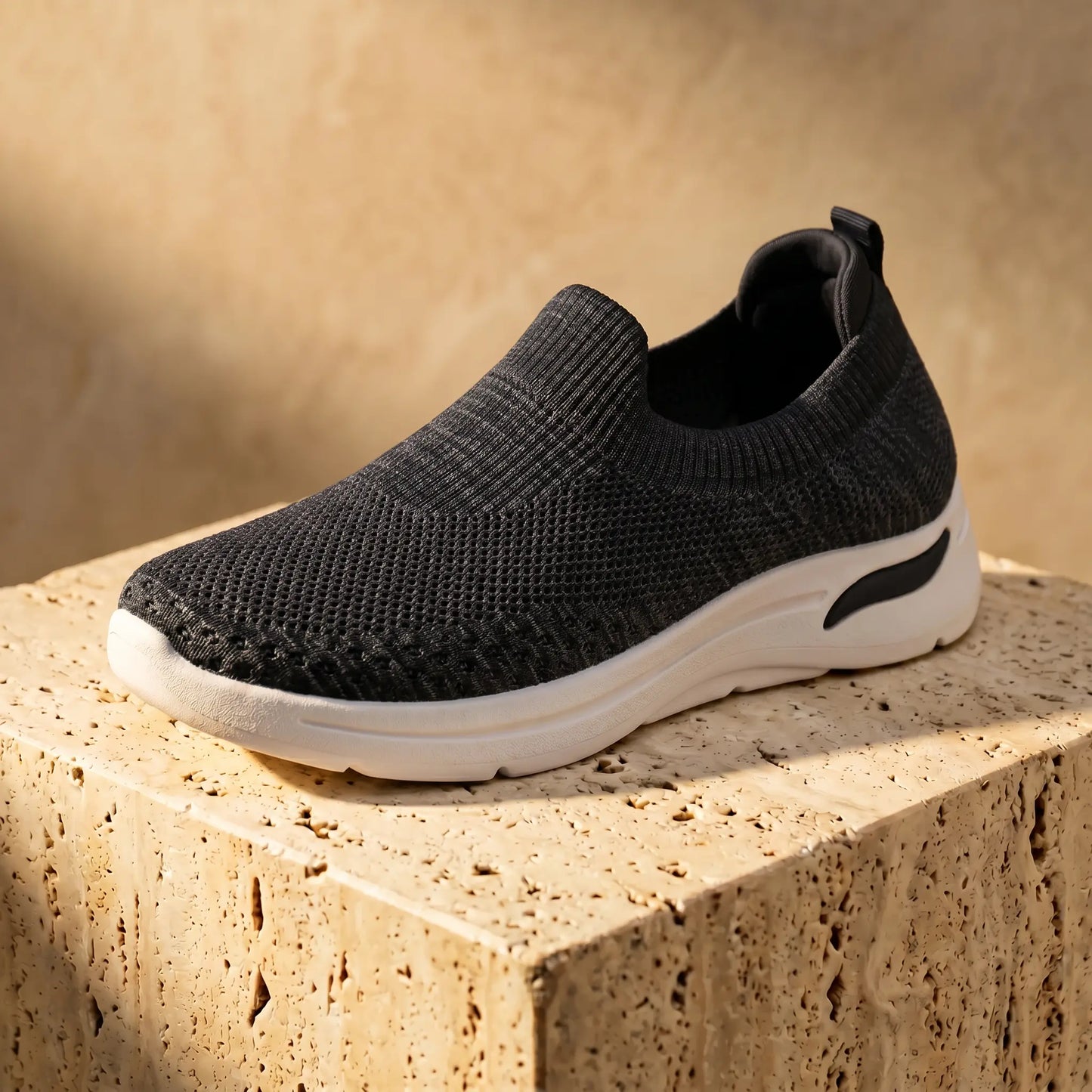 Zhivra women's midnight black knit slip-on sneaker with a breathable perforated upper and thick white platform sole, styled on a textured block.