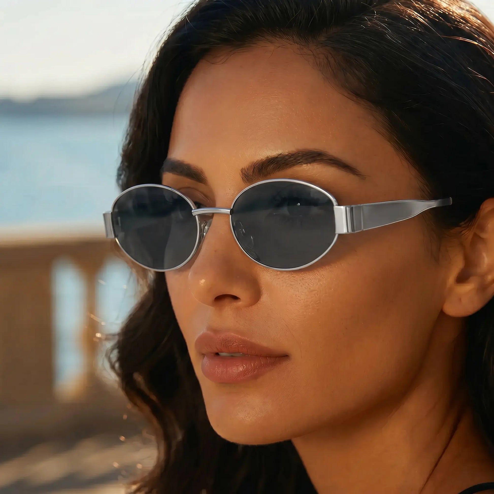 Model wearing Zokari Sterling Silver Oval Metal Frame Sunglasses with dark tinted lenses in an outdoor setting.