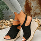 Black peep-toe espadrille wedge sandals with jute-wrapped heels, worn by a model with distressed jeans and an ankle bracelet. Focus on the bohemian chic style and comfortable height.