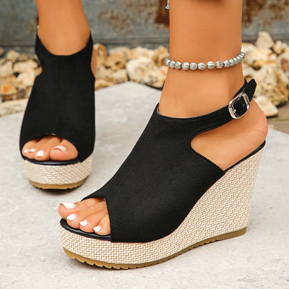 Close-up lifestyle shot of black Zoltan peep toe espadrille wedge sandals worn by a model, showcasing the jute-wrapped wedge and buckle ankle strap.