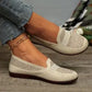 Women's warm beige Zoria knit loafers with crystal-embellished vamp and geometric pattern, shown on foot with denim jeans. Side view.