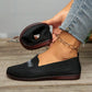 Black Zoria knit loafers with crystal embellishments on the vamp, shown on a woman's foot with denim jeans against a wooden floor.