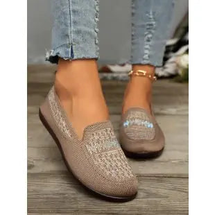 Zoria women's warm beige knit loafers with geometric pattern and crystal embellishments on the vamp, styled with denim jeans on a wooden floor.