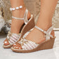Champagne gold embellished wedge sandals with white mesh vamp, delicate gold bows, and a crystal charm dangling from the adjustable ankle strap, worn on feet.