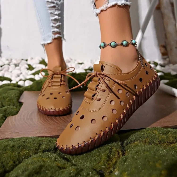 Model's feet wearing Zoryn women's breathable perforated loafers in rich brown, paired with distressed denim jeans and a turquoise anklet.