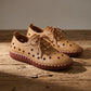Pair of Zoryn beige perforated lace-up loafers on a wooden surface, showcasing artisanal contrast stitching and a flat sole.