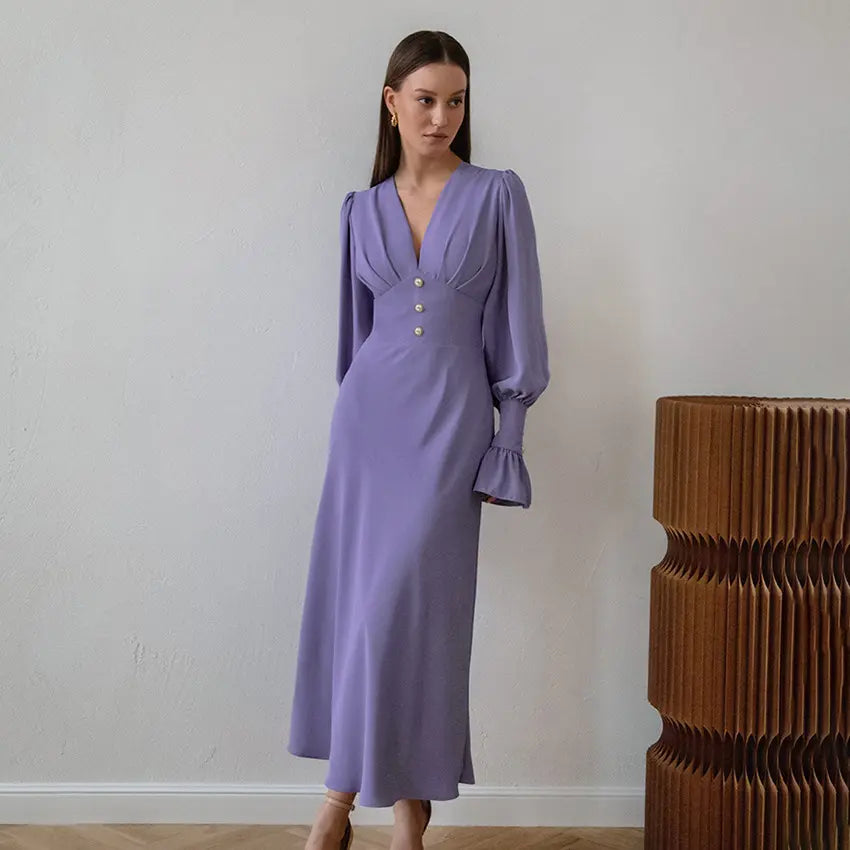 Zydra elegant midi dress in soft lilac chiffon, featuring a romantic V-neck, voluminous bishop sleeves, and pearl button details, shown on a model in a styled setting.
