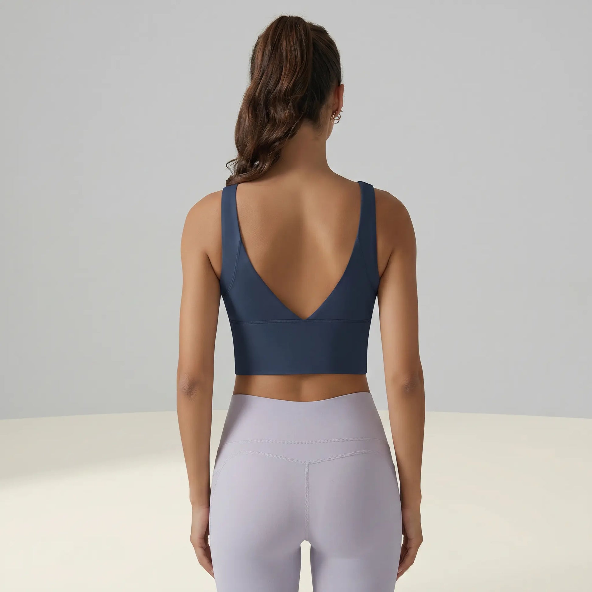 Deep blue Zykari V-Back Yoga Sports Bra on a model, rear view. Features a plunging V-design, wide supportive straps, and smooth performance fabric.