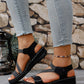 Close-up of women's black Zykla comfort sport sandals with elastic criss-cross straps and white stitching, styled with light-wash denim jeans.
