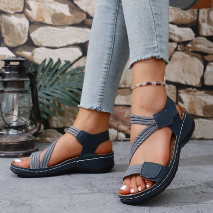 Women's Zykla comfort sport sandals in dark blue with beige elastic straps and white stitching, worn with jeans.