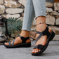 Zykla women's comfort sport sandals in black with criss-cross elastic straps and beige accents, worn with light-wash denim jeans.