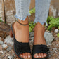 Black Zylaya women's wedge sandals featuring a layered floral applique, perforated strap, peep-toe, and a chunky 4cm wood-effect heel, shown on feet with distressed denim jeans.