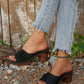 Zylaya women's black wedge sandals with a peep-toe, single strap adorned by a layered floral applique, and perforated detailing, worn with denim jeans.