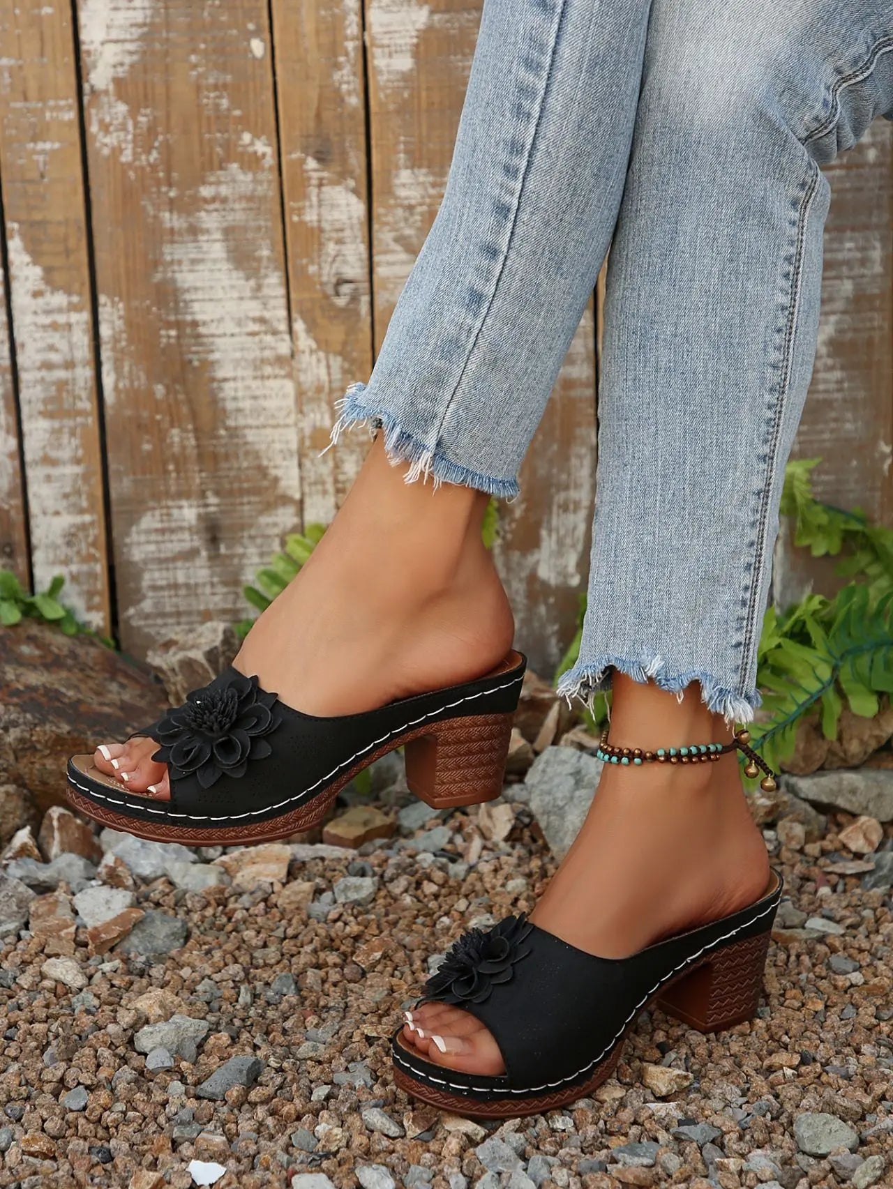 Zylaya women's black wedge sandals with a peep-toe, single strap adorned by a layered floral applique, and perforated detailing, worn with denim jeans.