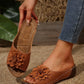 Tan Zylia women's slip-on sandals featuring a layered floral embellishment, perforated details, and white contrast stitching on a low wedge sole, styled on a foot with jeans.
