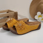 Zylia yellow floral embellished slide sandals with perforated straps and low wedge soles, styled with a straw hat and decorative flower.