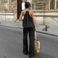 Model wearing a black Zyloria bohemian linen set, featuring a halter neck top and wide-leg trousers, shown from the back on a European street.