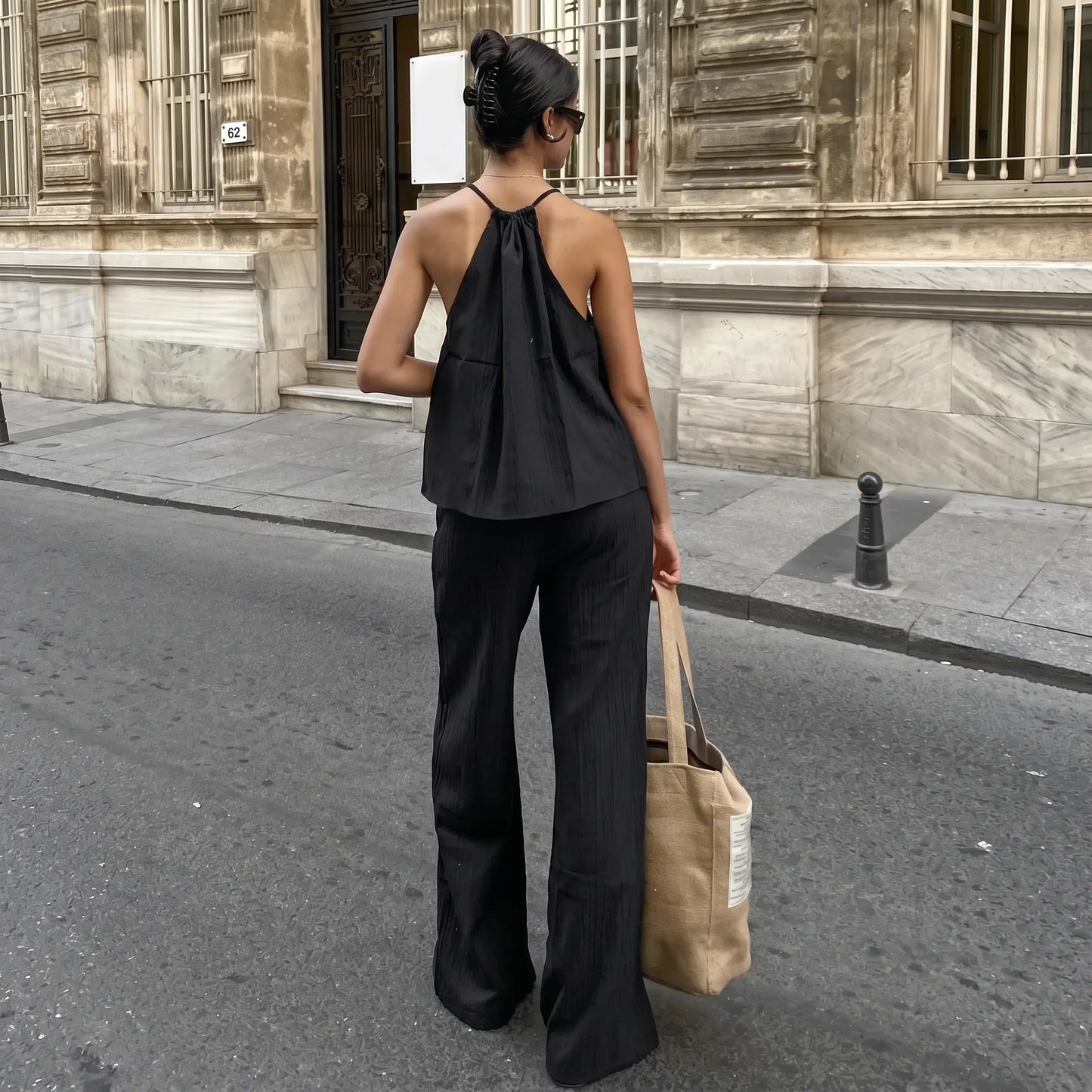 Model wearing a black Zyloria bohemian linen set, featuring a halter neck top and wide-leg trousers, shown from the back on a European street.