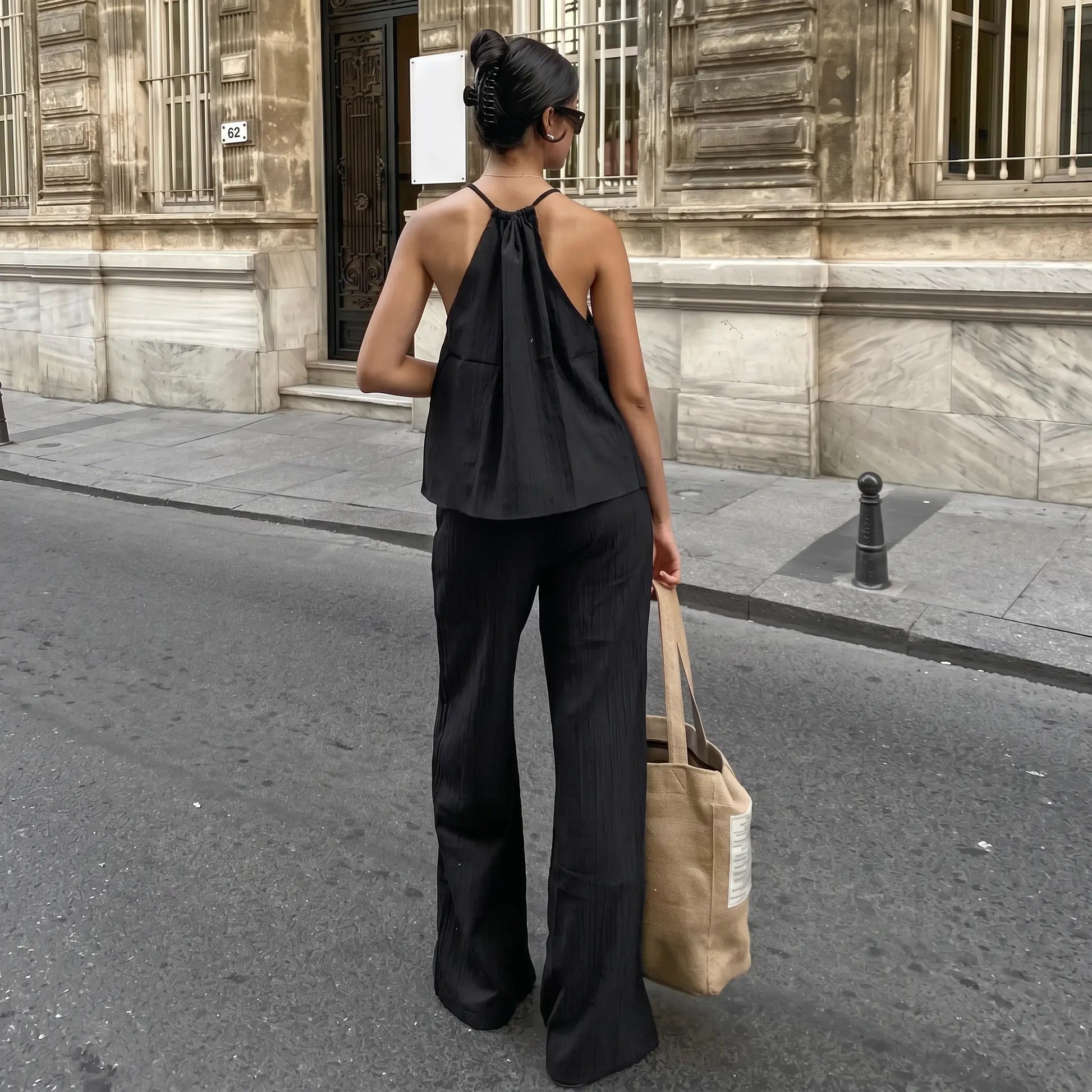 Model wearing a black Zyloria bohemian linen set, featuring a halter neck top and wide-leg trousers, shown from the back on a European street.