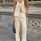 Woman modeling an oatmeal beige bohemian linen set featuring a halter tie-front top and wide-leg drawstring pants, shown in an outdoor urban setting.