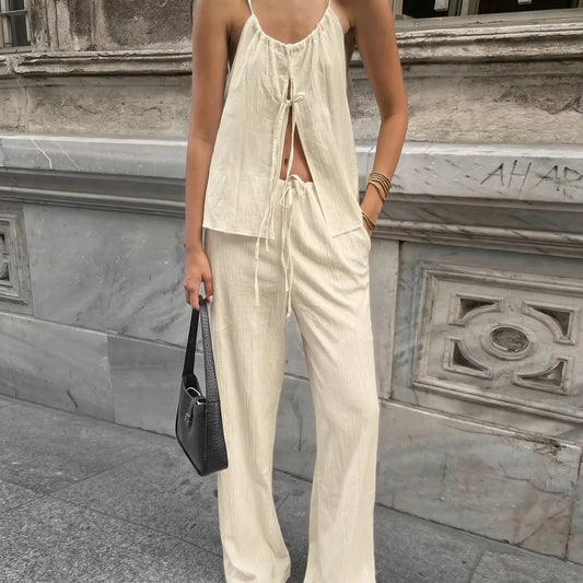 Woman modeling an oatmeal beige bohemian linen set featuring a halter tie-front top and wide-leg drawstring pants, shown in an outdoor urban setting.