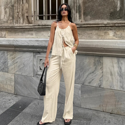 Woman wearing a Zyloria bohemian linen set in oatmeal beige, featuring a halter tie-top and flowing wide-leg trousers, styled with sunglasses and a handbag in an urban setting.