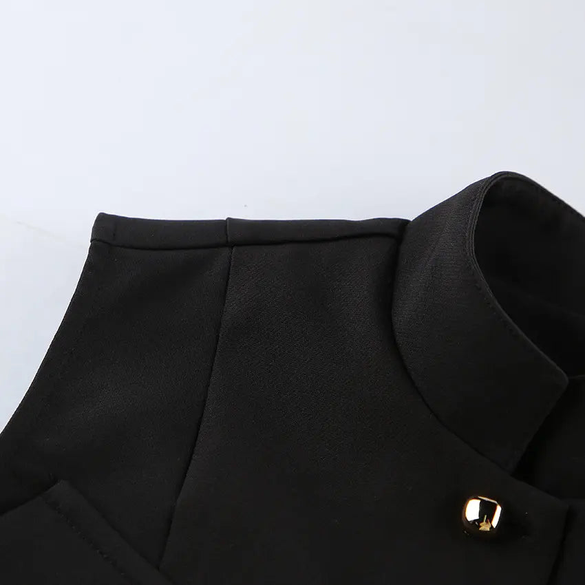 Close-up of a black Zylos sleeveless vest showcasing its structured mandarin collar and a polished gold-tone button detail.
