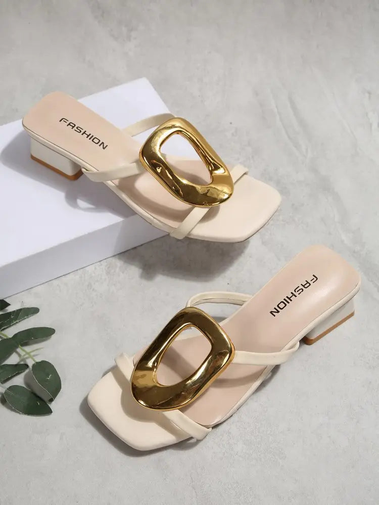 Pair of creamy ivory Zylos square toe slide sandals featuring large gold oval buckles and block heels, displayed in a flat-lay arrangement with subtle branding on the footbed.