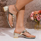 Zylos metallic gold thong sandals with floral crystal embellishments and a 4cm chunky block heel, shown on a model's feet with a clean pedicure and anklet in a studio setting.