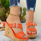 Orange Zylos peep-toe wedge sandals featuring a distinctive cork-effect heel with multi-colored flecks and a silver adjustable buckle strap, styled with distressed denim jeans on a woman's feet outdoors.