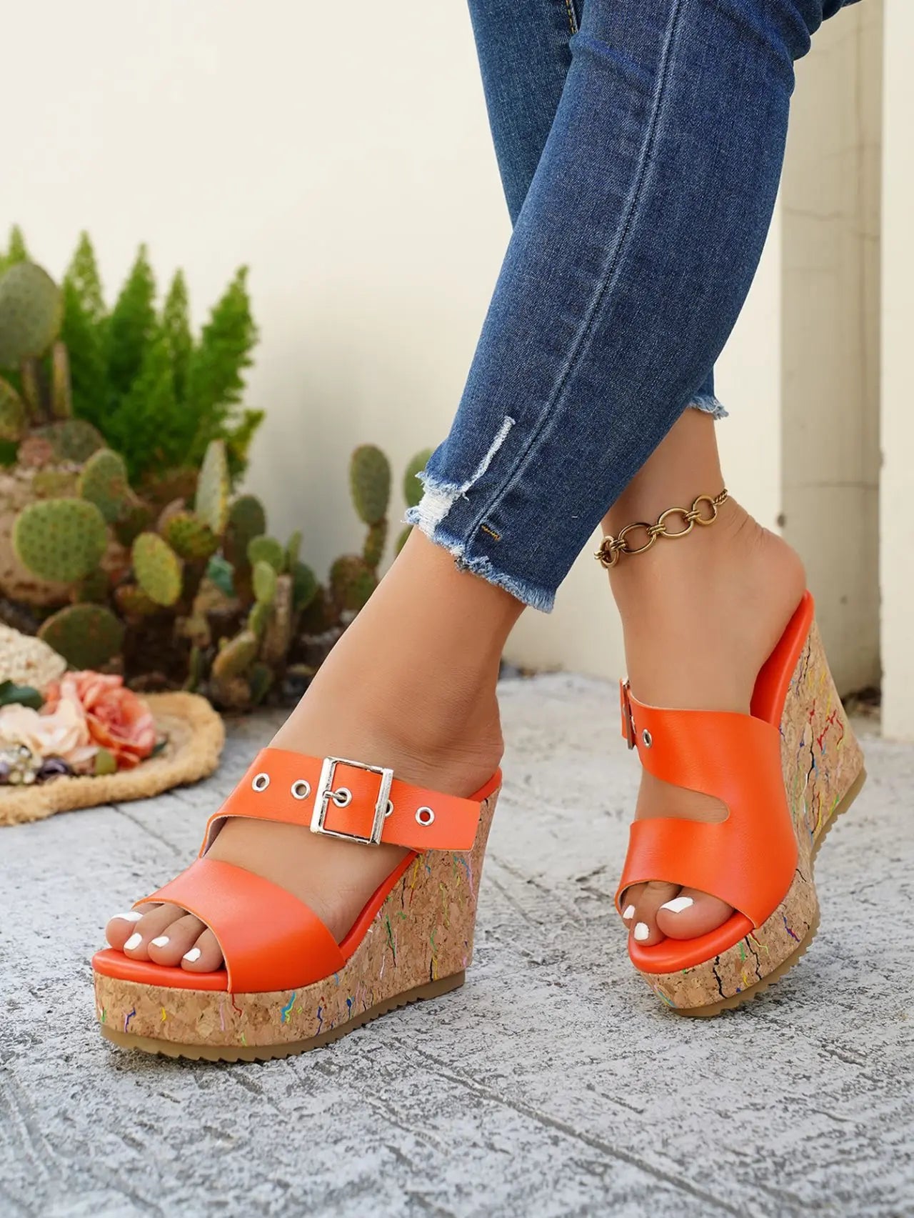 Zylos women's vibrant orange peep-toe wedge sandals styled with distressed denim jeans and a silver buckle strap, showcasing the multi-colored flecked cork wedge and rubber sole.
