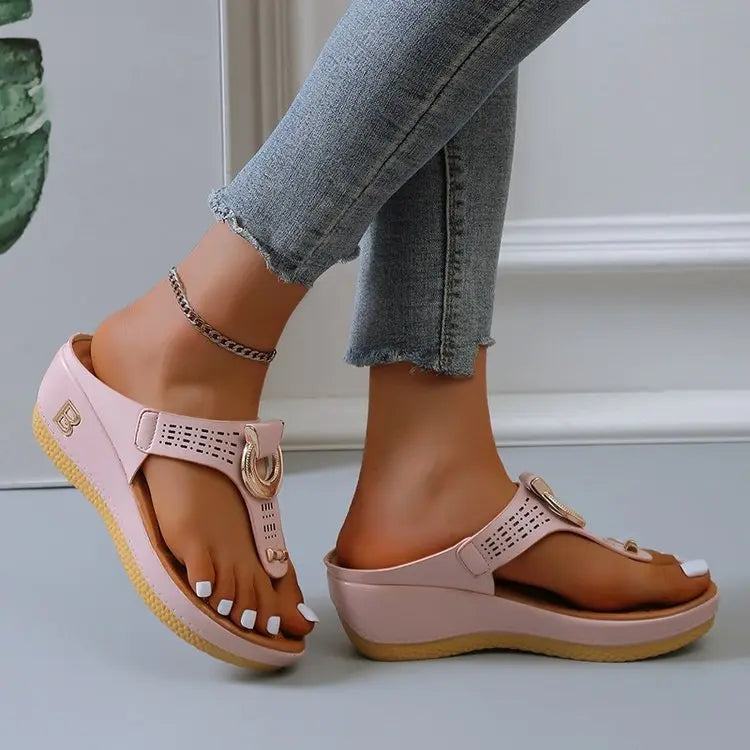 Women's light pink Zylos wedge platform thong sandals with gold ring hardware and perforated straps, worn with distressed jeans and an anklet.