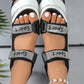 Top-down view of black Zylos sporty chic platform sandals adorned with sparkling rhinestone 'Sport' text on hook-and-loop straps, showcasing white-painted toes and a white sculpted sole.