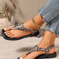 Elegant Zylos snake print flat sandals with a square toe and adjustable ankle strap, shown on a model's feet paired with distressed denim.