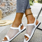 Woman's feet wearing white Zylos breathable mesh flat sandals with faux leather straps and a silver buckle, shown in an outdoor setting.