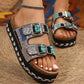 Close-up of a foot wearing Zylpha embellished platform slide sandals in classic black, featuring intricate beadwork, rhinestones, and turquoise stones on twin adjustable buckle straps.