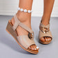 Beige Zylva women's wedge sandals featuring a chic gold-tone ring detail and elastic straps, shown on a model's feet with a peep-toe design and layered wedge heel.