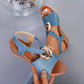 Blue Zylva women's wedge sandals with a gold ring detail on the vamp strap, shown on a foot with a Pearl ankle bracelet, showcasing the peep-toe design and layered wedge heel.