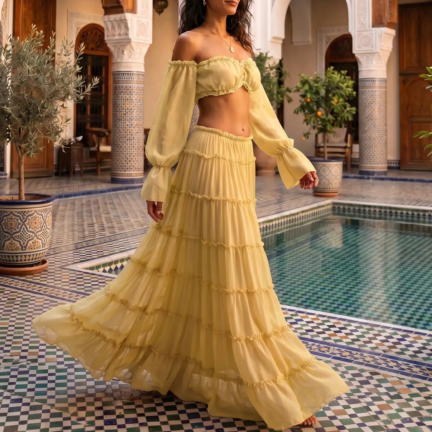 Sunlit Lemon Zymeth bohemian off-shoulder tiered maxi set, with bell sleeves and a flowing five-tier skirt, worn by a model walking in a resort courtyard.