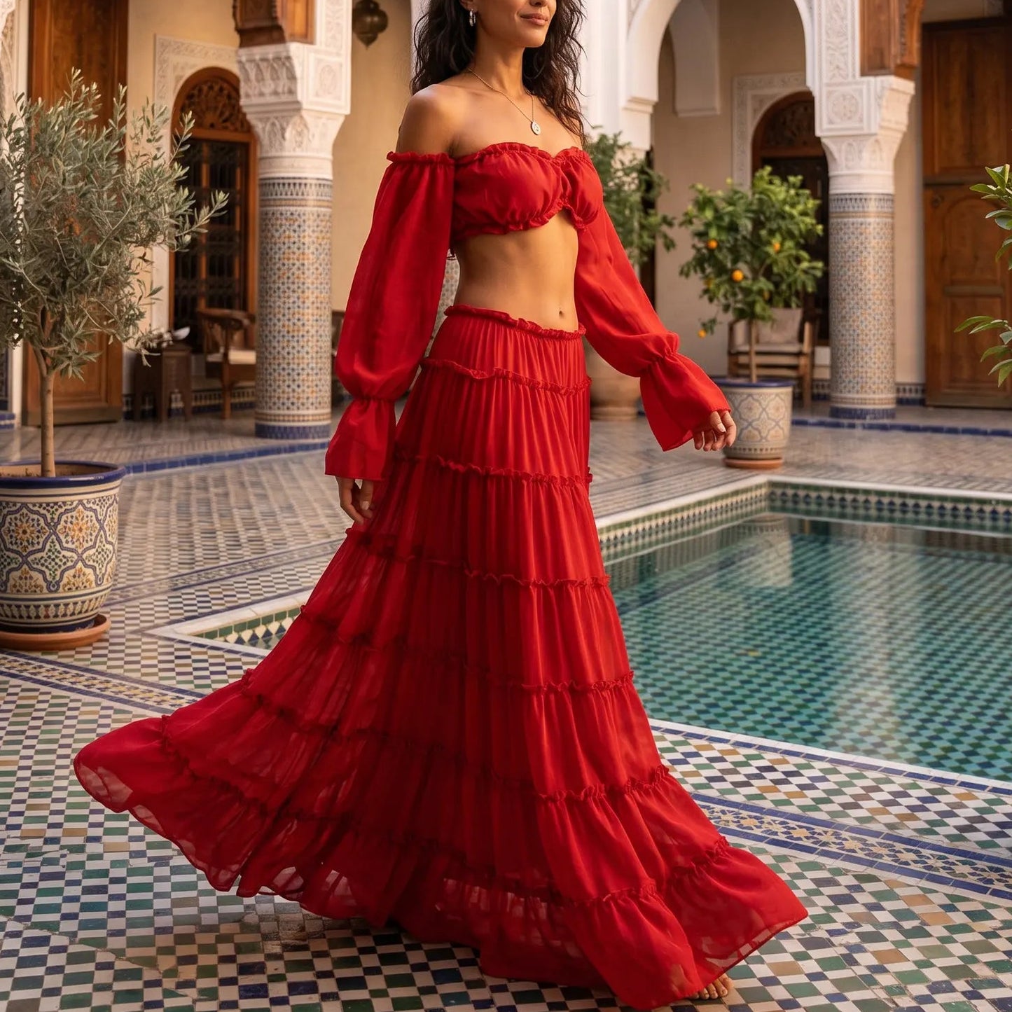 Model in a vibrant crimson Zymeth off-shoulder tiered maxi set, with a ruffled cropped top and voluminous five-tier skirt, by a Moroccan riad pool.