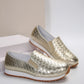 A pair of Zymir metallic gold slip-on loafers with a woven texture, displayed at a three-quarter angle on a studio background.